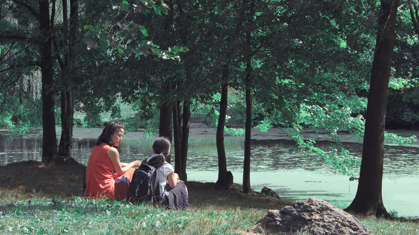 A still from Advantageous: Gwen and Jules sitting on the grass in a park.